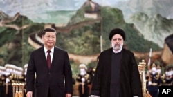 Iranian President Ebrahim Raisi, right, walks with Chinese President Xi Jinping 